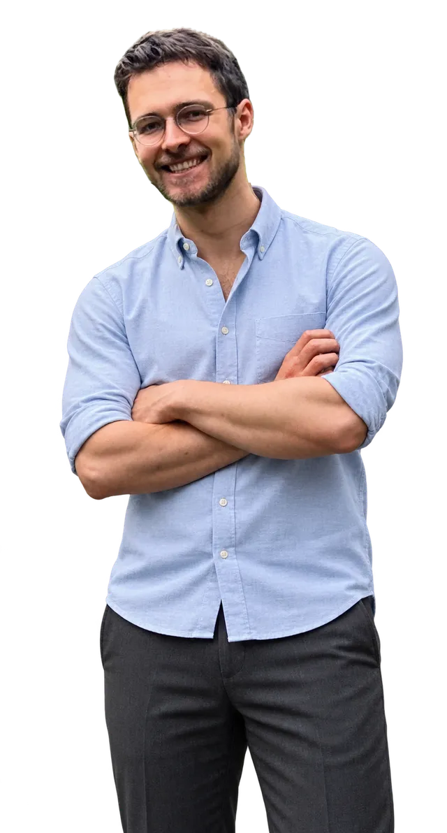 Johannes Roth smiling, in a light blue Oxford shirt with rolled sleeves and his arms crossed