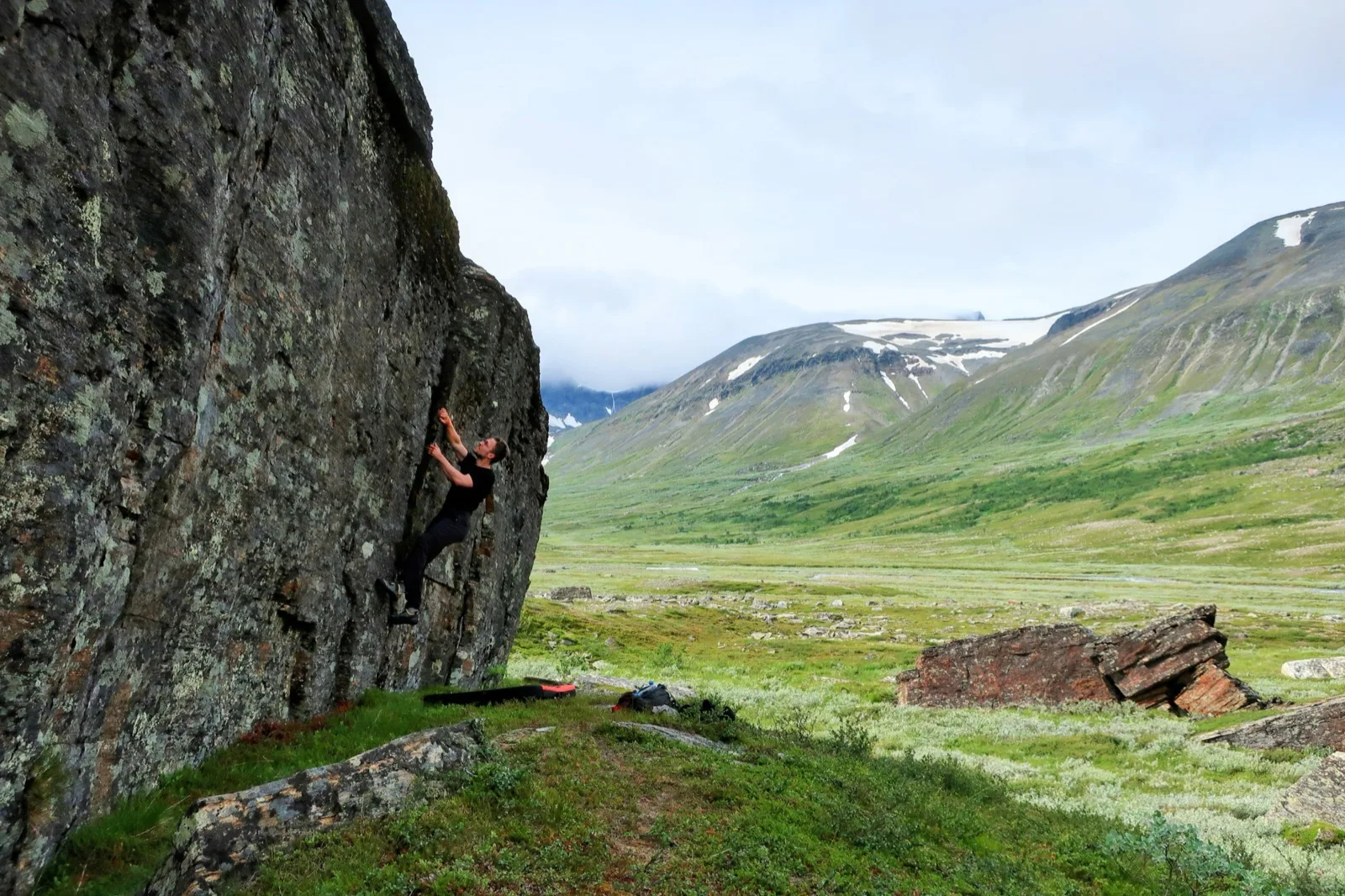 Johannes bouldering on a rock face in a mountain valley